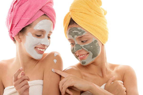 Two young women with towels on head and facial masks