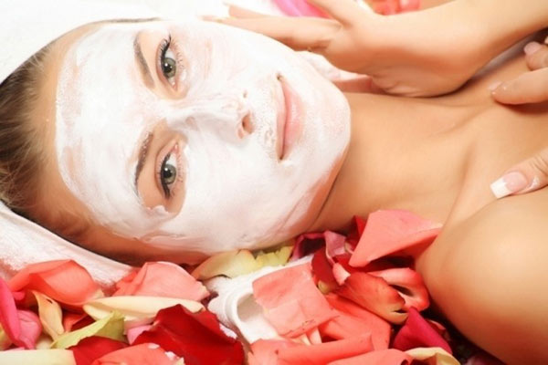 Woman with white face mask surrounded by flower petals