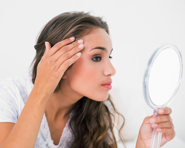 Woman examining her skin in mirror