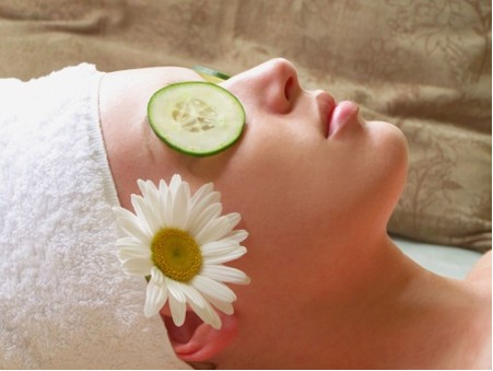 Woman with cucumber slice on eye and flower tucked by her ear