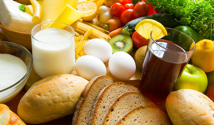 Assorted food on display, including milk, white eggs, bread, fruits and vegetables