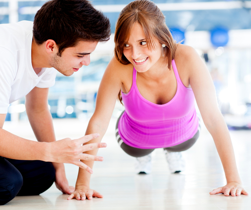 Personal trainer teaching exercise to woman