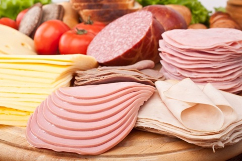 Assorted deli meat slices on wooden table