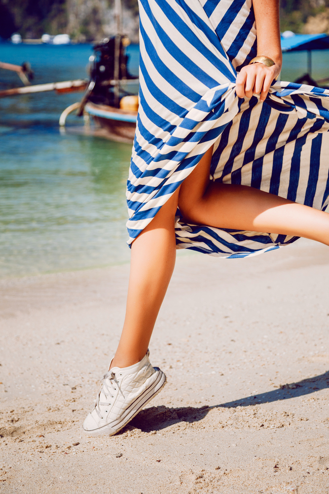 Woman's running legs in sneakers at the beach