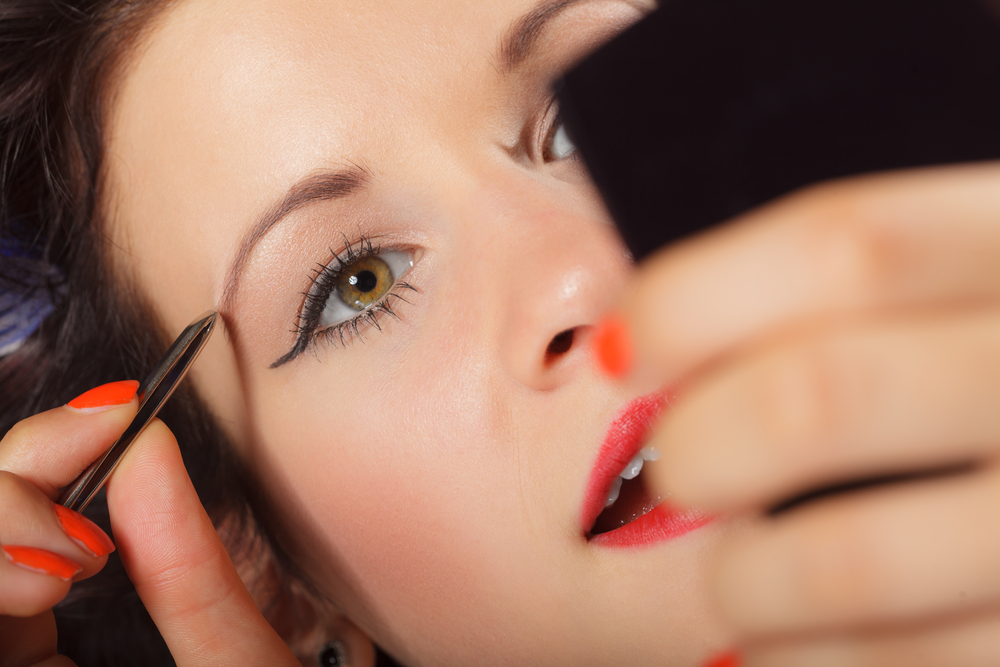 Woman tweezing eyebrows.