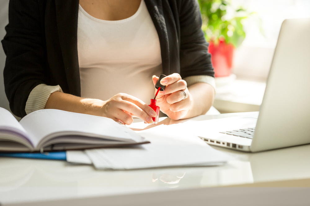 Woman applying nail polish at work