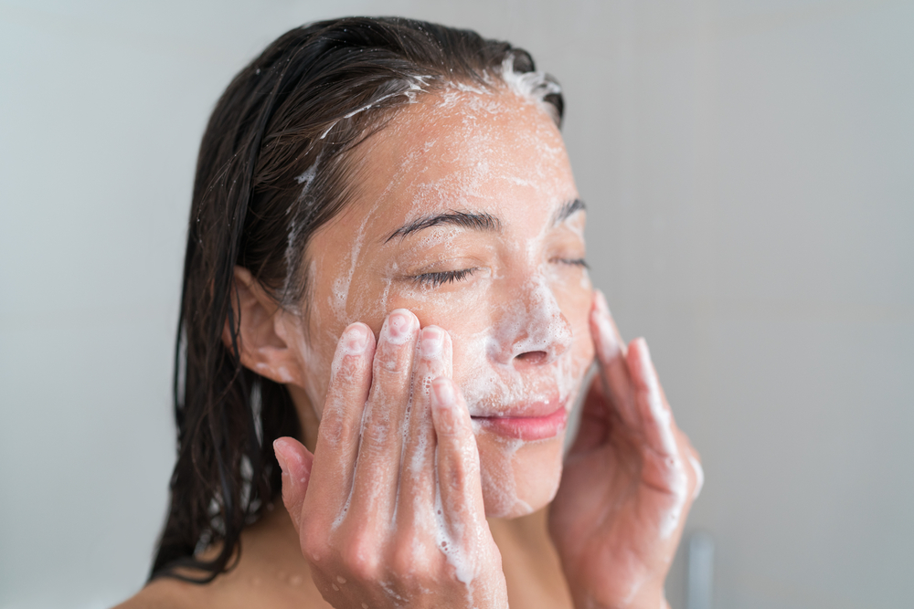 Woman exfoliating face with cleansing product