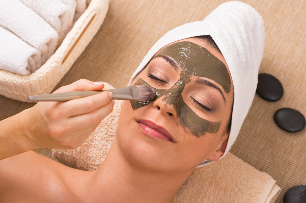 Woman applying exfoliating face mask