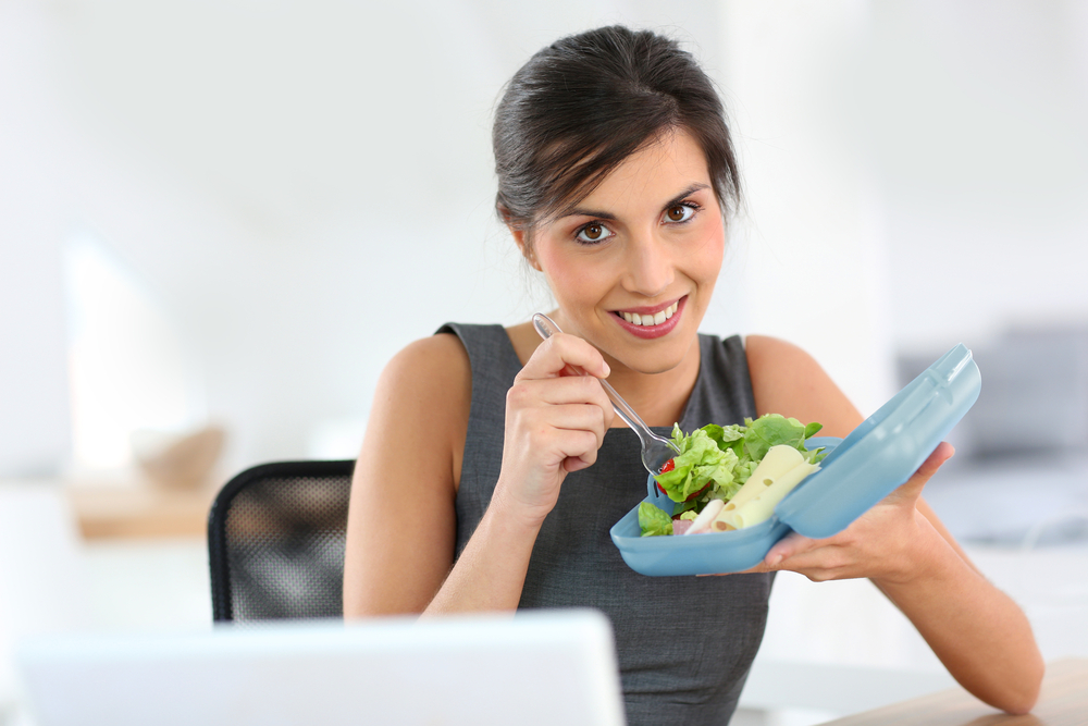 Woman eating salad from blue Tupperware