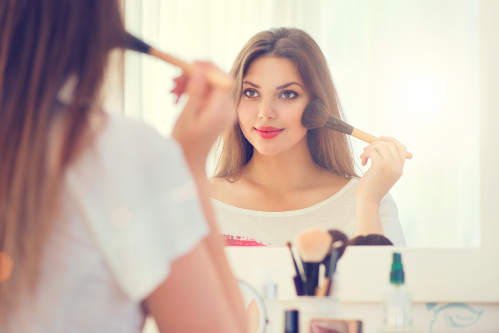 Woman applying blush to cheeks