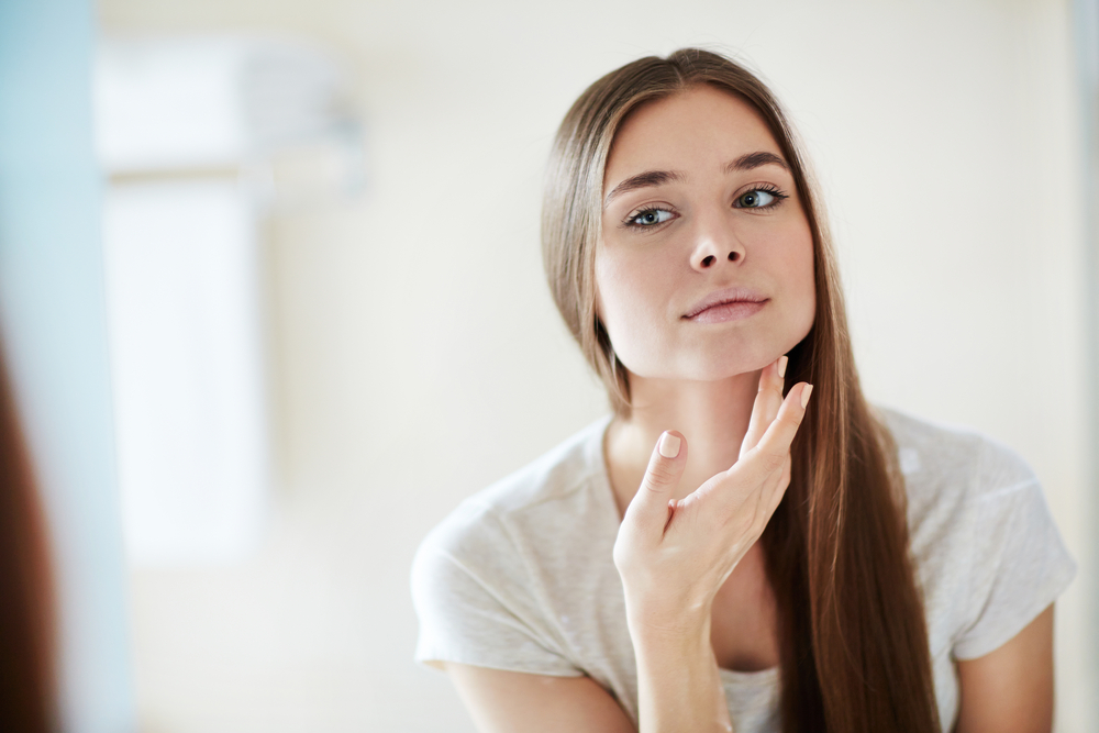 Woman checking face in mirror