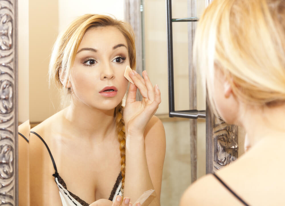Woman removing makeup in mirror