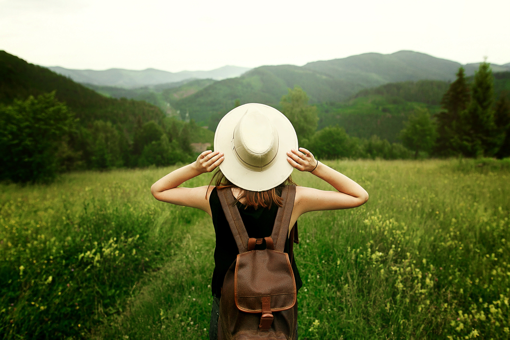 Female traveler surrounded by green fields and mountains