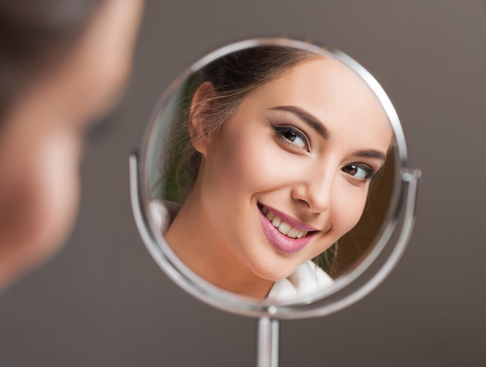 Face of smiling woman reflected in mirror