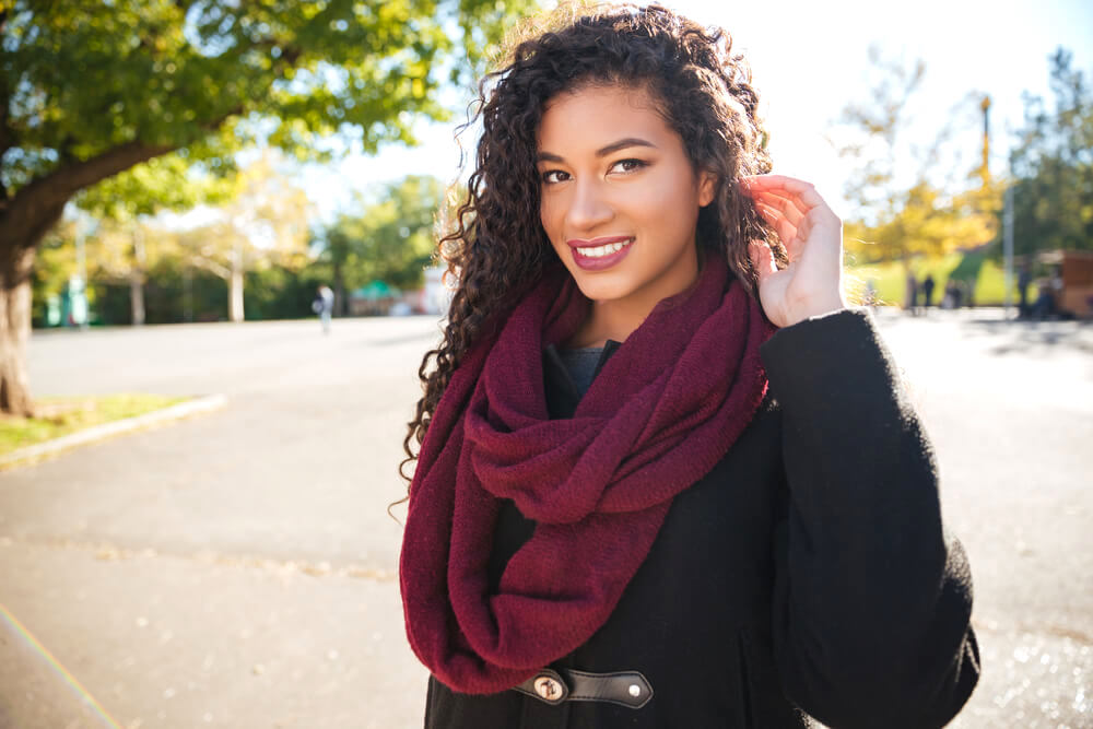 Smiling woman tucking her curly hair behind her ear