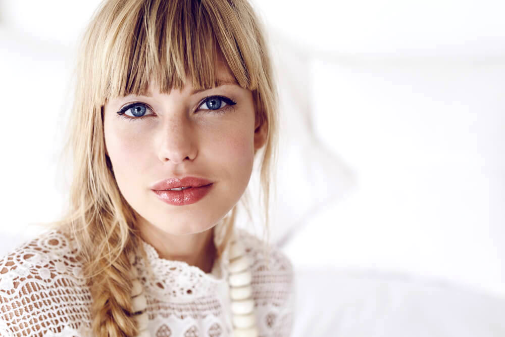 Close-up portrait of woman with long blonde hair in braids and straight hair bangs