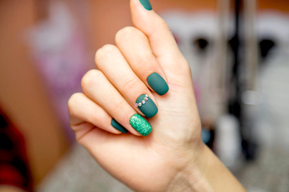 Green manicure with glitter and rhinestones