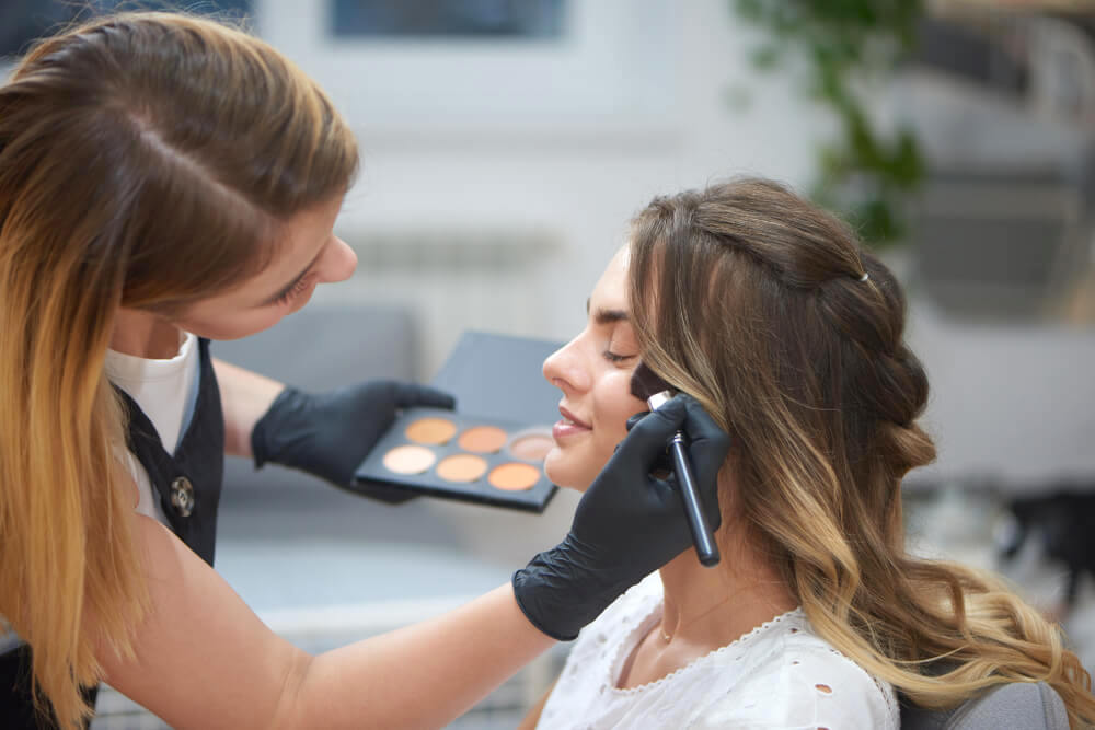 Makeup artist applying highlighter on model's face