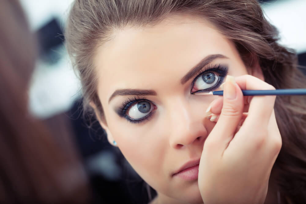 Woman applying black eyeliner to lower waterline