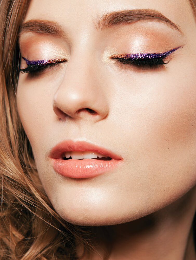 Woman with purple glitter eyeliner and beige eyeshadow