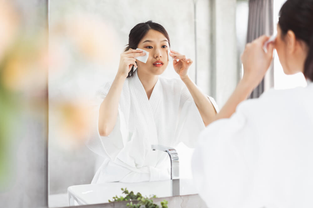 Woman applying skincare with cotton pads