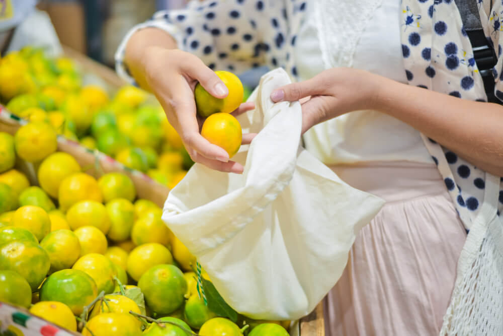 Woman putting fruit into reusable produce bag