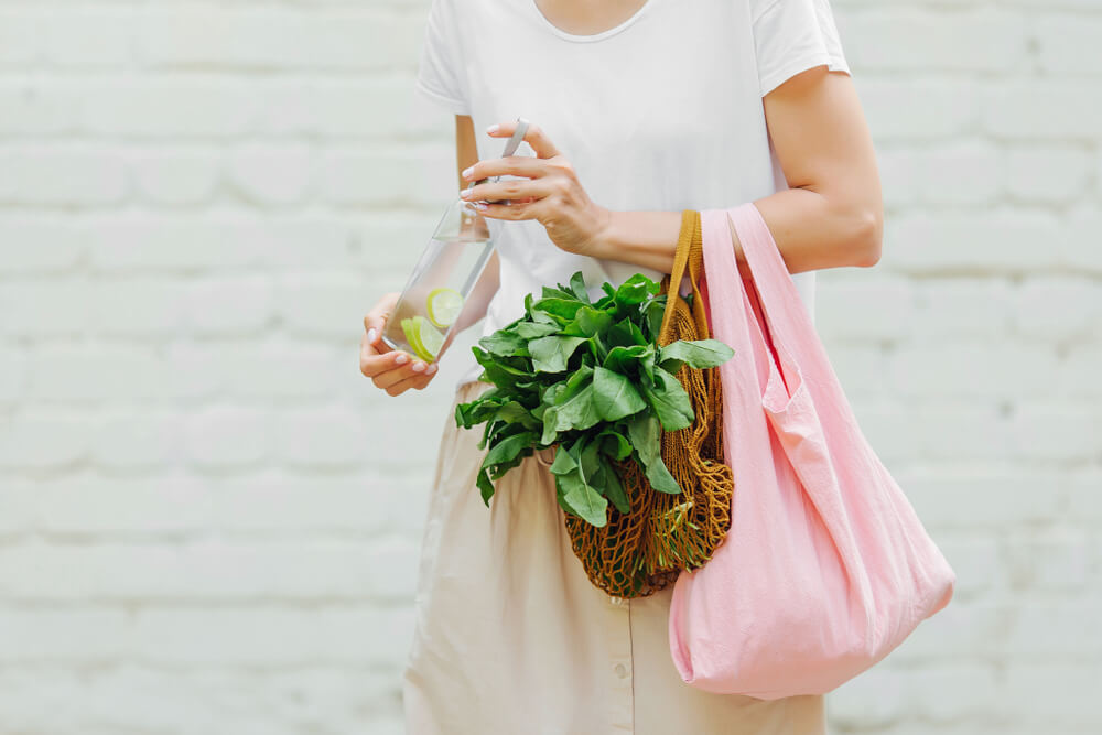 Woman holding reusable bags with groceries