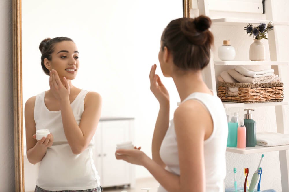 Woman applying moisturizer to face