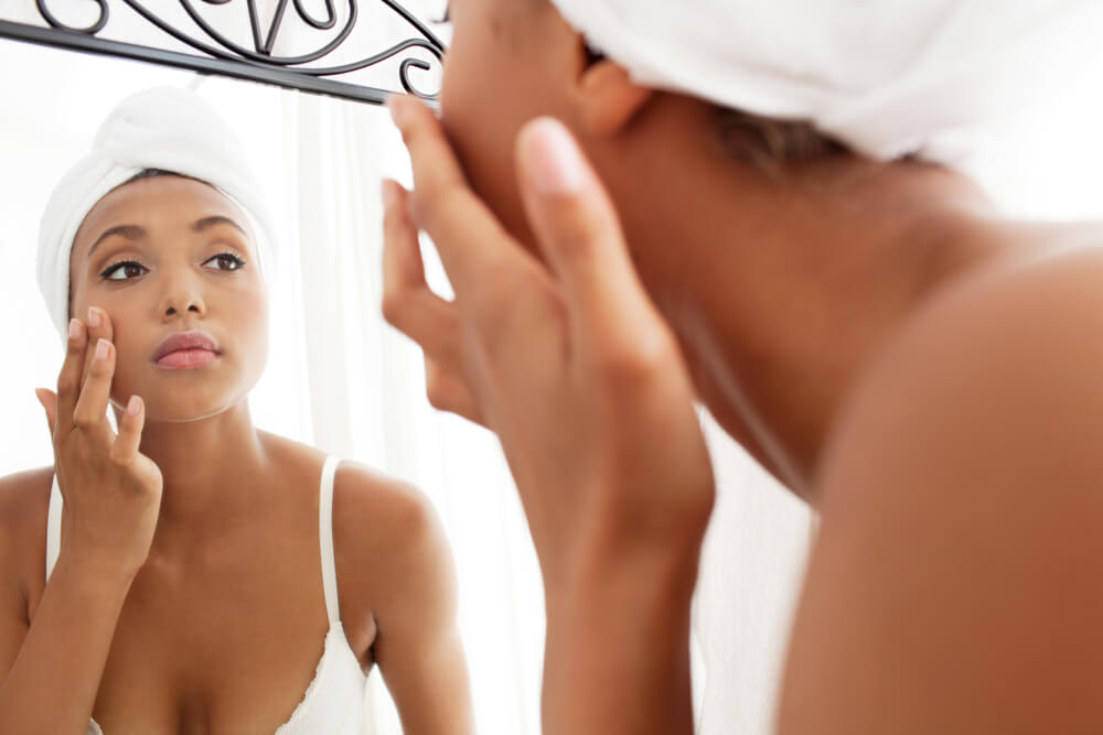 Woman looking at skin in mirror