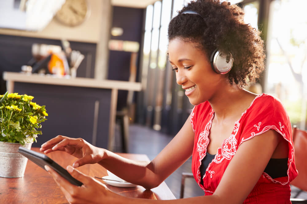 Woman at table looking at tablet with headphones on