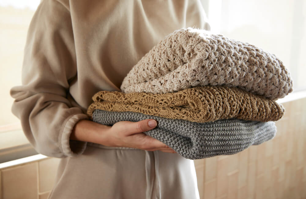 woman holding sweaters