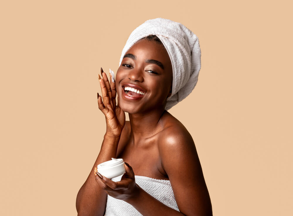 smiling woman applying moisturizer