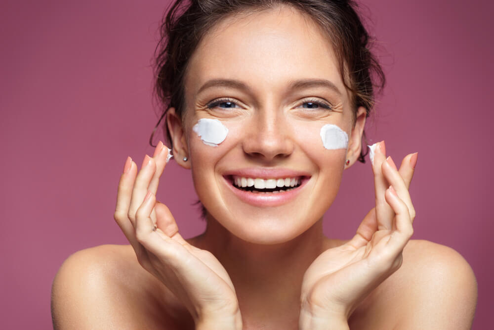 smiling woman applying moisturizer