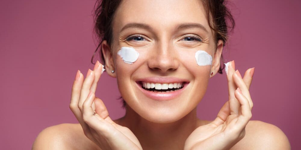 smiling woman applying moisturizer